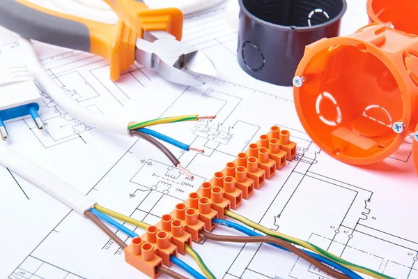 Electrical connectors with wires, junction box and different materials used for jobs in electricity. Many tools lying on diagrams. — Stock fotografie