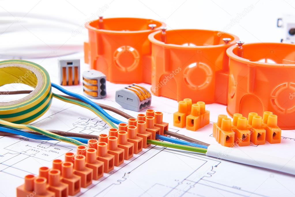 Electrical connectors with wires, junction box and different materials used for jobs in electricity. Many tools lying on diagrams.