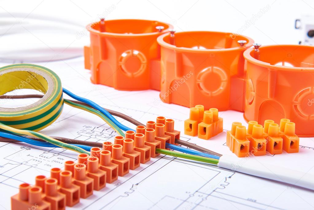 Electrical connectors with wires, junction box and different materials used for jobs in electricity. Many tools lying on diagrams.