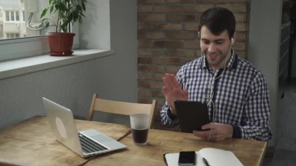 L'homme au petit matin assis dans un café, buvant du café et parlant à travers la tablette . — Video