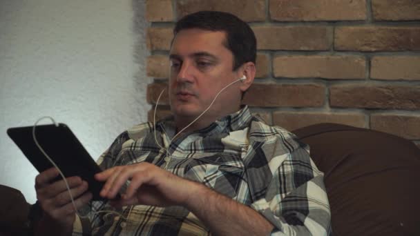 Man in de oortelefoon praten via tablet. — Stockvideo
