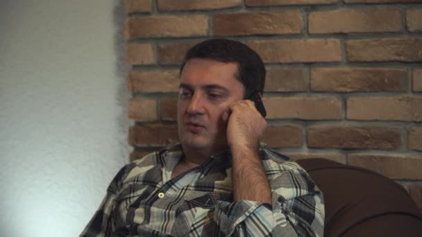 Mies lepää tuolissa ja puhuu älypuhelimella. . — kuvapankkivideo