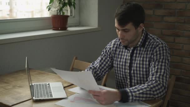 Um homem olha para a mesa e faz uma nota no caderno . — Vídeo de Stock