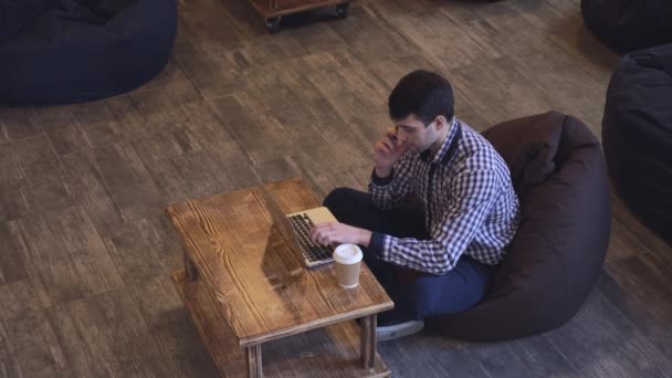 Centrado en el trabajo de un hombre hablando por teléfono y trabajando en su portátil . — Vídeos de Stock