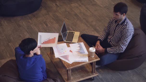 A woman holds a graph, a man takes a sip of coffee and typing on the keyboard. — Stock Video