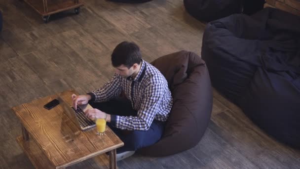 Manager seduto in coworking e lavora per un computer portatile sul tavolo è succo d'arancia . — Video Stock