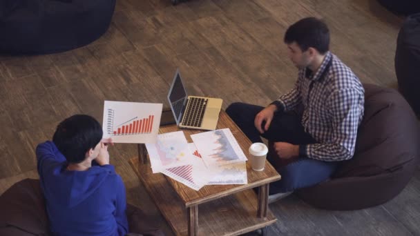 Une femme tient le planning de croissance, un homme tapant sur un ordinateur portable . — Video