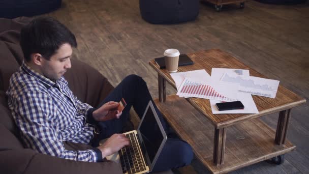 Homme avec un ordinateur portable et une carte de crédit pour payer la facture . — Video