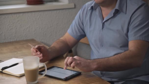 Középkorú férfi fizeti a számlákat a kezében a hitelkártyát az interneten. — Stock videók