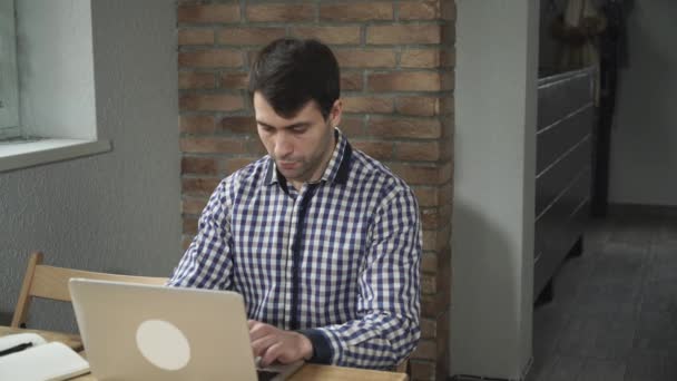 En kjekk mann som jobber med datamaskinen, på bordet, notatbok og penn . – stockvideo