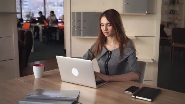 Una mujer de negocios escribiendo en su portátil en el lugar de trabajo de la oficina — Vídeos de Stock