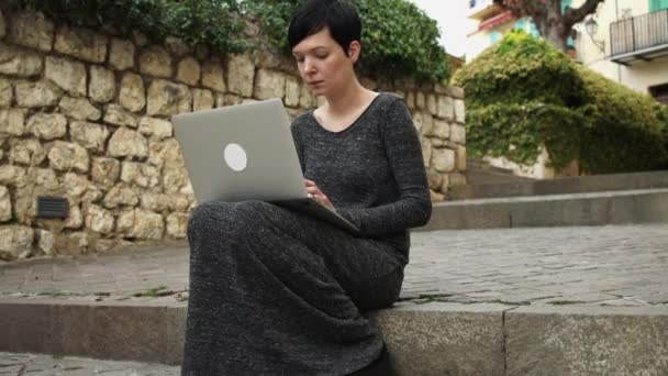Kendine güvenen iş kadını merdivenlerde oturan dizüstü bilgisayar kullanarak. — Stok video