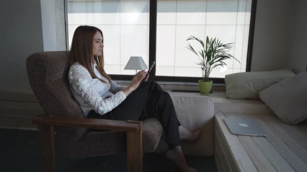 Donna che legge il libro sul tablet touch screen nella stanza con interior design in stile country — Video Stock