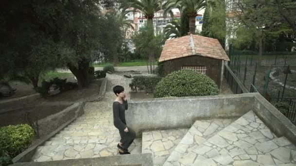 Mujer sube escaleras en el parque llamando en el teléfono inteligente . — Vídeo de stock