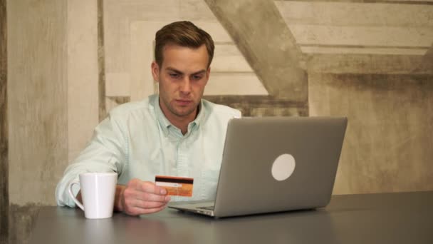 Online-Banking. der Mann sitzt am Tisch und hält die Kreditkarte. — Stockvideo