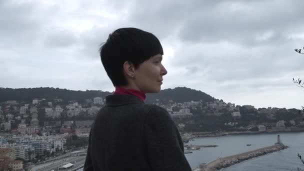 Donna che guarda la vista sulla città. Indossa un cappotto grigio . — Video Stock