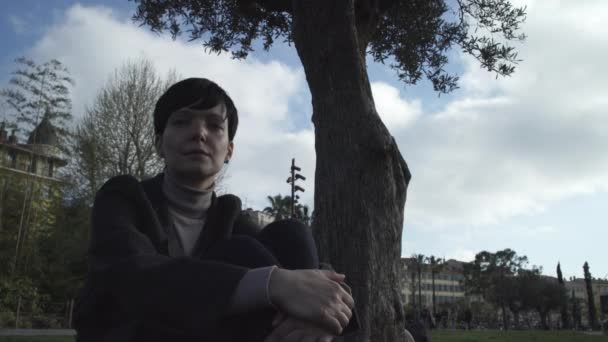 Frau sitzt am Wochenende unter Baum im Park. — Stockvideo