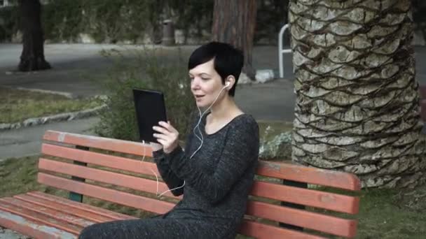 Mujer que utiliza la aplicación en la tableta de pantalla táctil para videollamada en el patio . — Vídeos de Stock