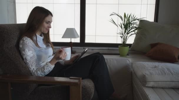 Vrouw ontspannen thuis lezen berichten op de tablet van de Aanraking scherm. — Stockvideo