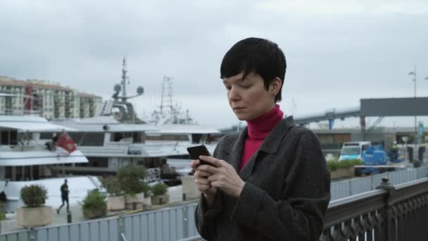 Γυναίκα γραπτών μηνυμάτων sms, χρησιμοποιώντας την εφαρμογή στο smartphone στο λιμάνι. — Αρχείο Βίντεο