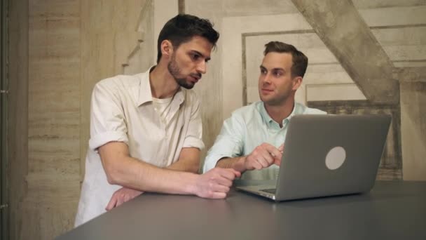 Zwei befreundete Männer blicken auf den Computer und lachen. — Stockvideo