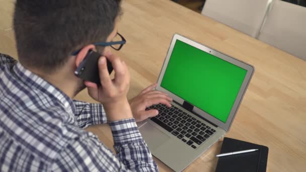 Człowiek biznesu rozmawia na komórkę i wpisując na komputerze. — Wideo stockowe
