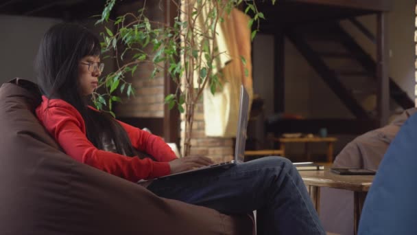 Asian woman working on the laptop in loft with wooden stairs. — Stock Video