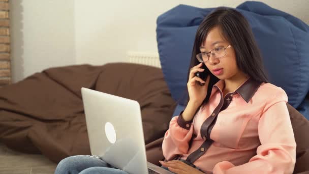 Jonge Aziatische vrouw praten aan de telefoon zitten op de stoel van de zak bonen — Stockvideo