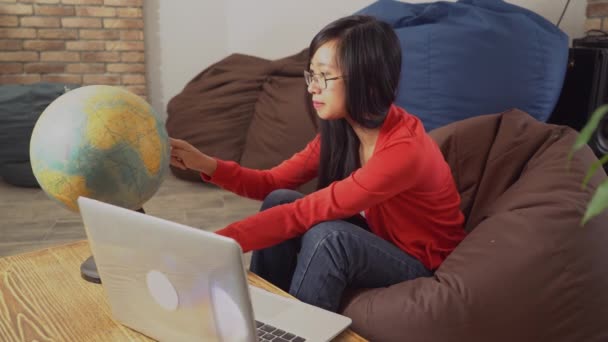 Frau mit langen schwarzen Haaren rotiert um die Welt und wählt Land. — Stockvideo