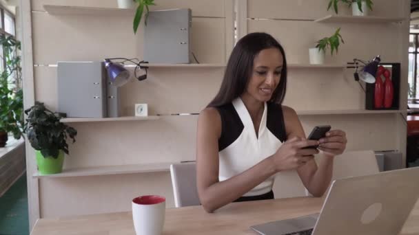 Gülümseyen kadın modern ofis cep telefonunda sms okumak. — Stok video