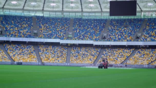 大きなスタジアムの芝生の水まきトラクター. — ストック動画
