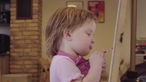 La niña pinta sobre un lienzo, dejando y esperando su aprobación . — Vídeo de stock