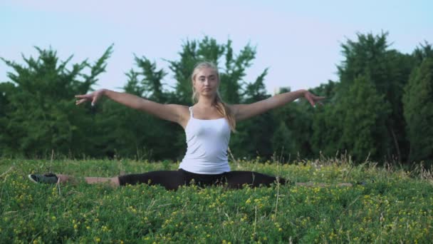 Jong meisje in shirt voert oefening helling op de heuvel met groen gras. — Stockvideo