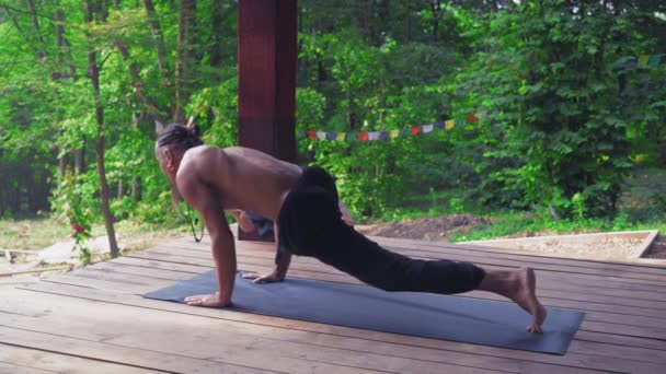 El hombre realiza ejercicios de yoga, levantando una pierna y doblando la otra . — Vídeo de stock