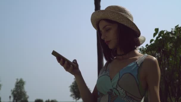 Una joven con un sombrero ganando un mensaje por teléfono . — Vídeos de Stock