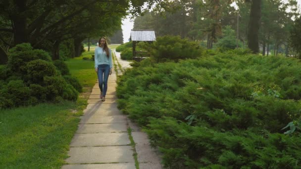 En ung flicka går på banan i parken sommaren leende och glädje. — Stockvideo