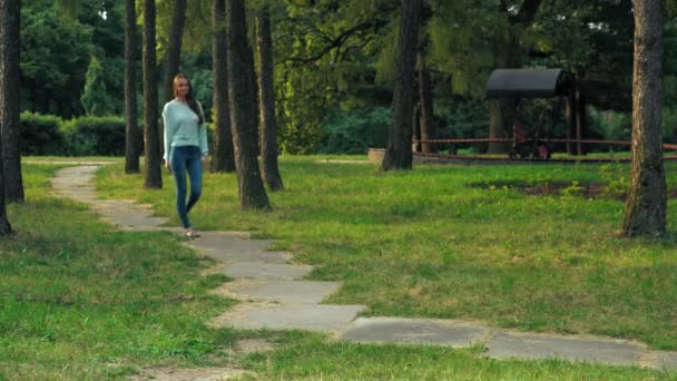 年轻的黑发女孩是在公园里的道路上. — 图库视频影像