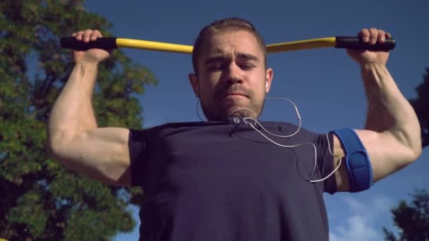 Snygg hane med smartphone på muskulös hand på Open Air gym. — Stockvideo