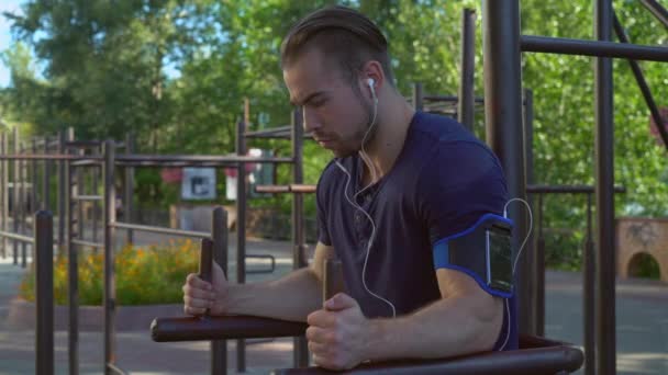 Bodybuilder trains outdoors with mobile application — Stock Video