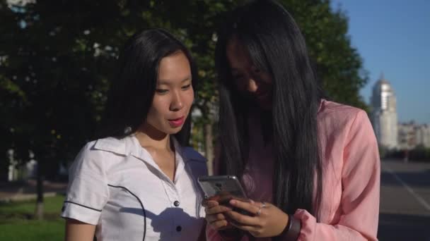 Duas mulheres segurando celular conversando sorrindo . — Vídeo de Stock