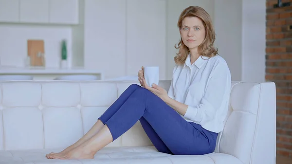 Geschäftsfrau sitzt mit einer Tasse Tee auf der Couch lizenzfreie Stockfotos