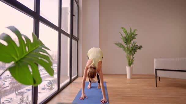 Female in sportswear stretching near window — стоковое видео