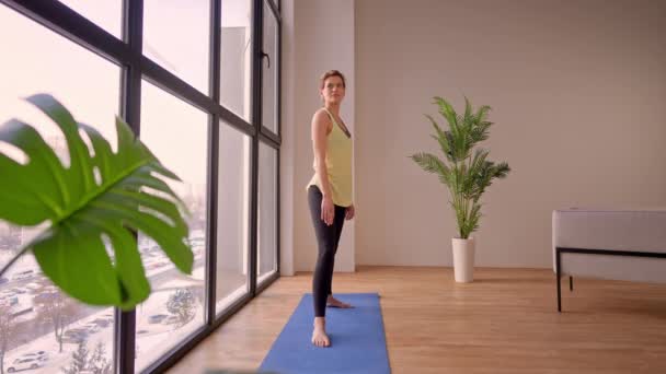 Female in sportswear stretching in flat — стоковое видео