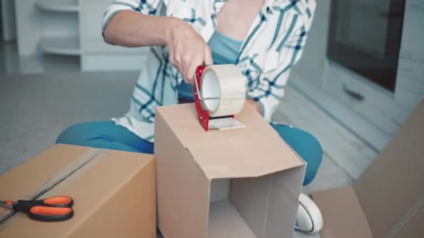 Женщина с помощью клейкой ленты упаковать пункт — стоковое видео