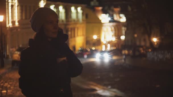 Mujer en la calle de la noche bebiendo café y hablando por teléfono — Vídeos de Stock