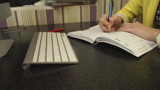 Un estudiante con una chaqueta amarilla escribiendo en un cuaderno — Vídeos de Stock