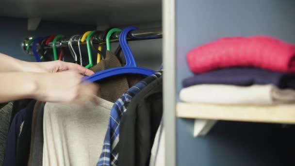 Одежда висит на вешалках у шкафа с одеждой — стоковое видео