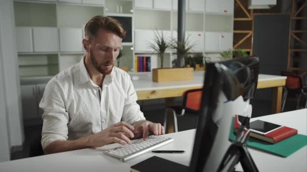 Ein zufriedener Geschäftsmann sitzt in seinem Büro und arbeitet an seinem Computer. — Stockvideo