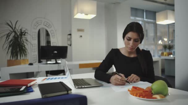 Kvinnan arbetar och äta skivor av morötter och äpplen. — Stockvideo