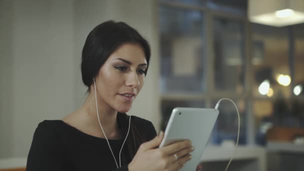 Uma mulher no escritório conversando com um tablet e sorri — Vídeo de Stock